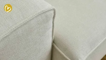 Deteilaufnahme eines weißen Sofa-Stoffes, mit erkennbarem Saum und Naht